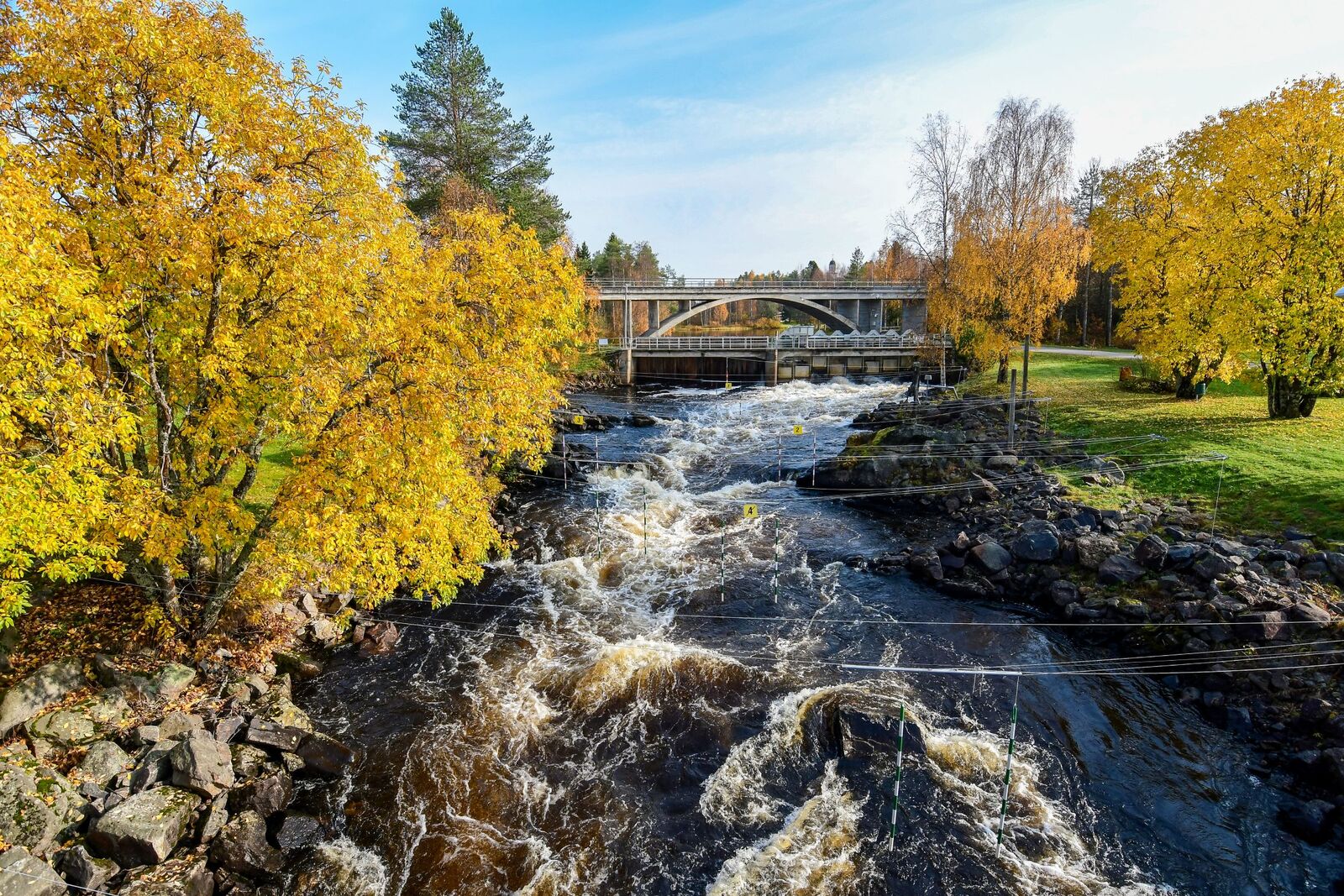 Ruskatunnelma kosken rannalla, lehtipuiden lehdet ovat muuttuneet keltasävyisiksi.