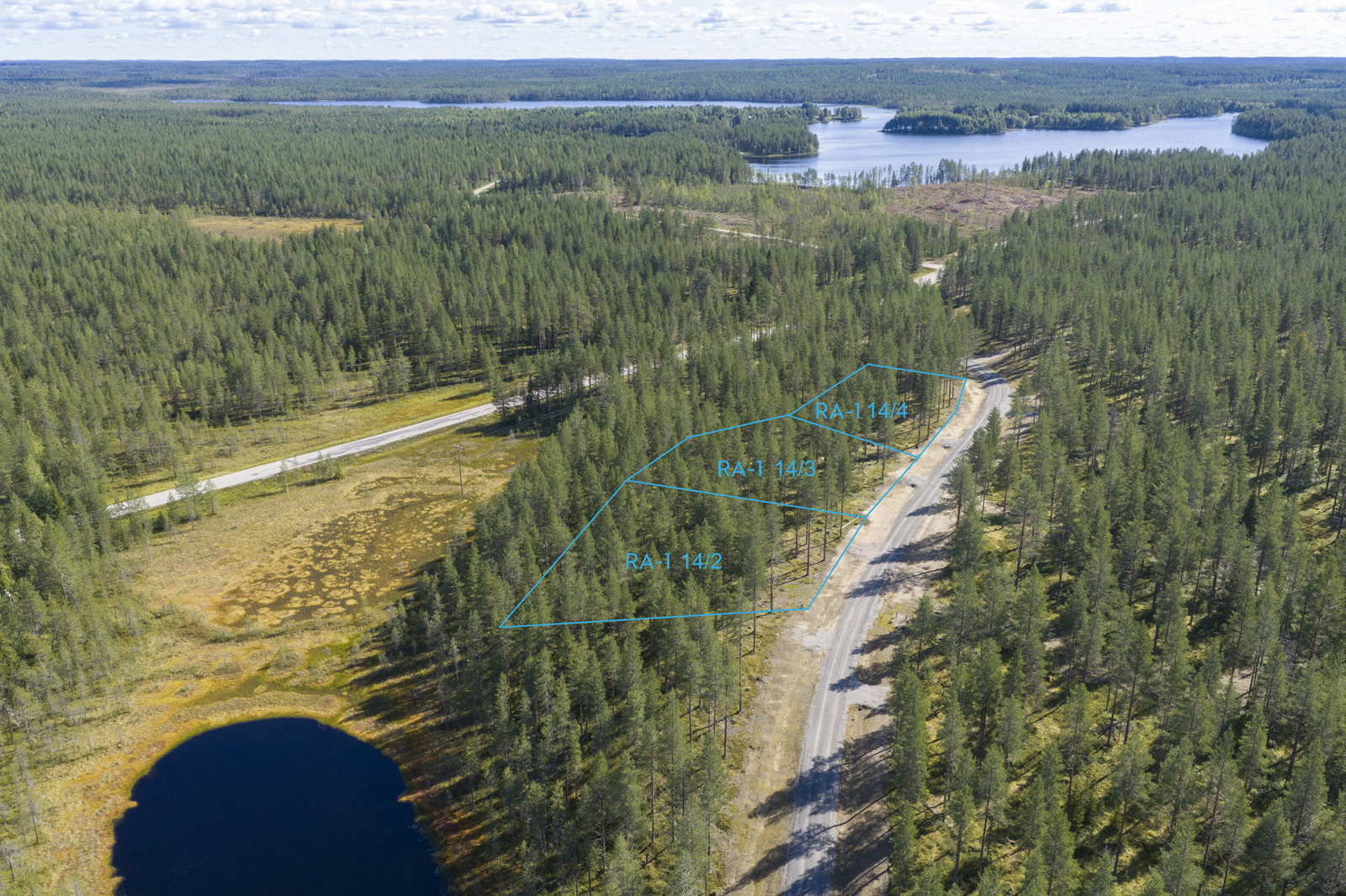 Kesäinen järvimaisema. Etualalla pieni lampi. Tien varrelle on merkitty kolme tonttia. Ilmakuva.