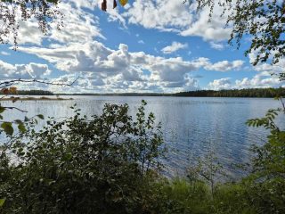 Maisema järvelle, aurinko paistaa, taivaalla on pilviä, vastaranta näkyy kaukaisuudessa.