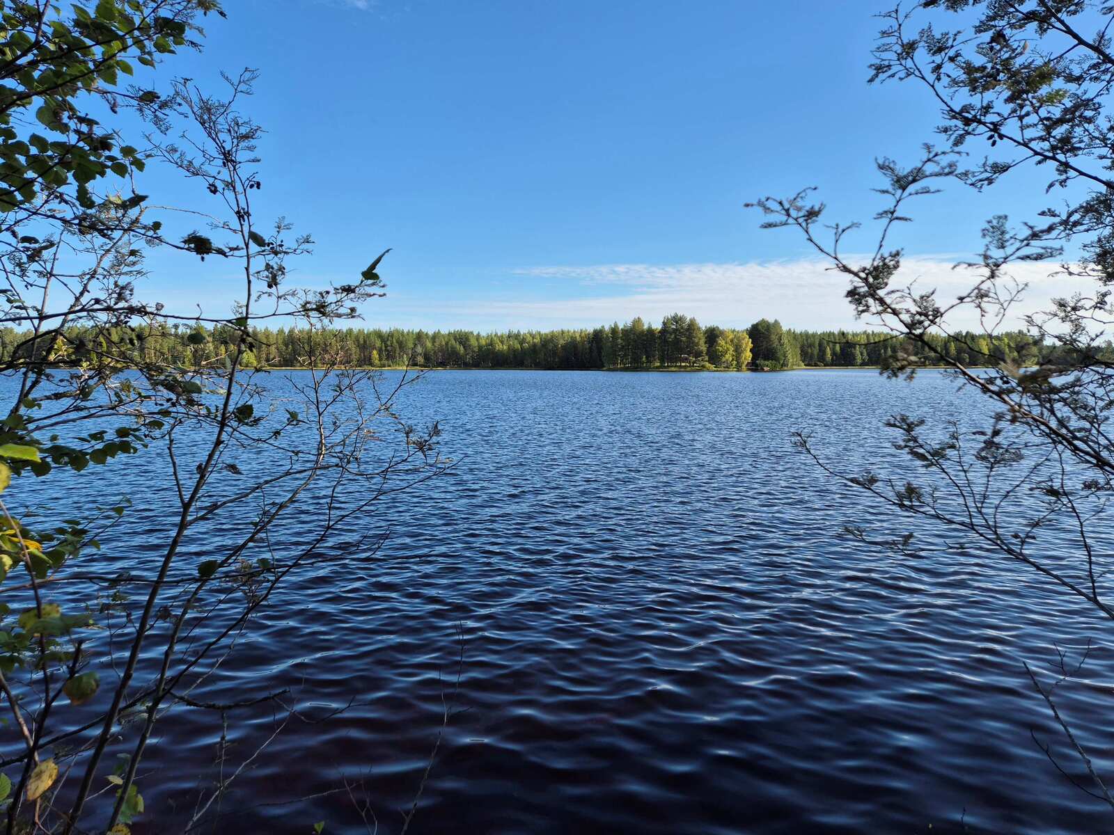 Tuulessa kevyesti aaltoileva järvi, vastarannalle paistaa aurinko.