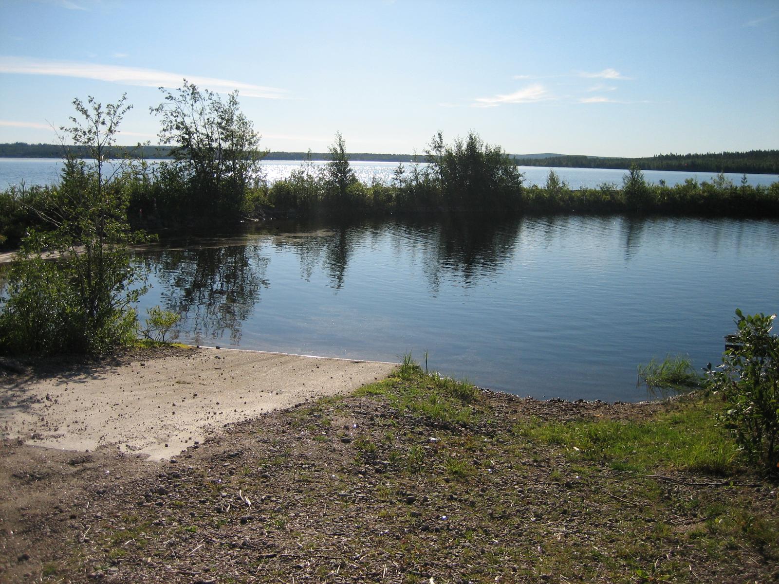 Kesäisessä järvimaisemassa etualalla on veneenlaskupaikka ja taustalla aallonmurtaja.