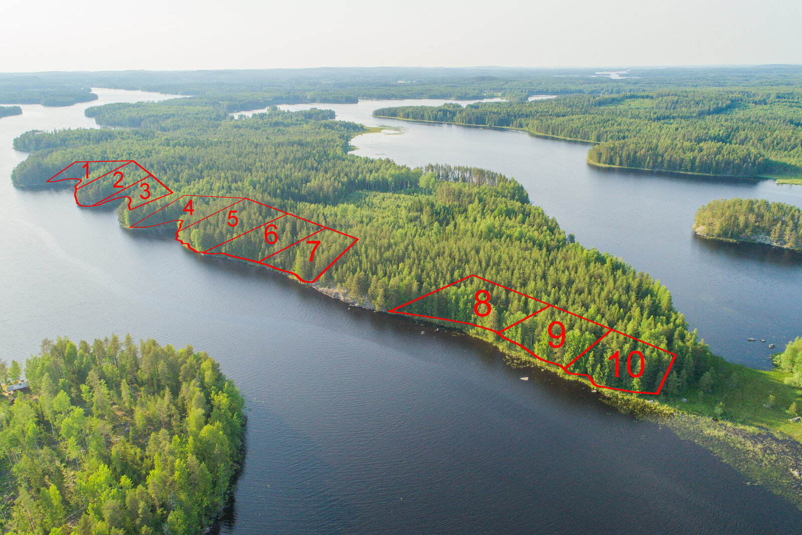 Vesistö ympäröi metsäistä saarta, jonka rantaan on piirretty kymmenen tontin kaavat. Ilmakuva.