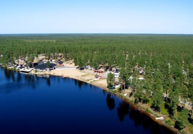 Järven rannalla on leirintäalue, jota ympäröi mäntymetsä. Ilmakuva.