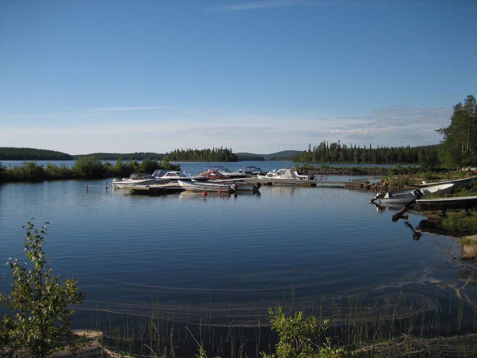 Kesäisessä järvimaisemassa veneenlaskupaikalla on veneitä kiinnitettynä laituriin.