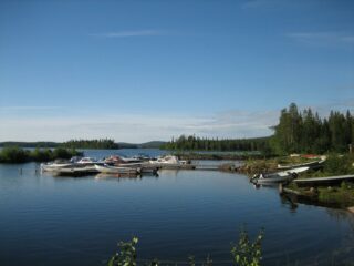 Kesäisessä järvimaisemassa veneenlaskupaikalla on veneitä kiinnitettynä laituriin.