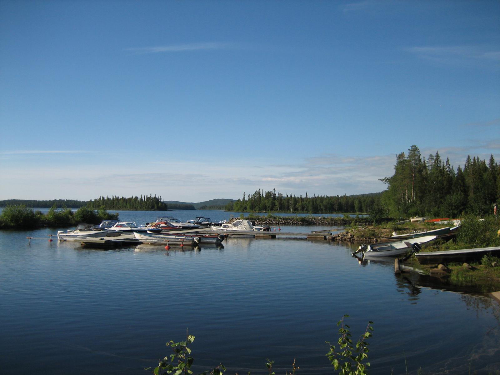 Kesäisessä järvimaisemassa veneenlaskupaikalla on veneitä kiinnitettynä laituriin.