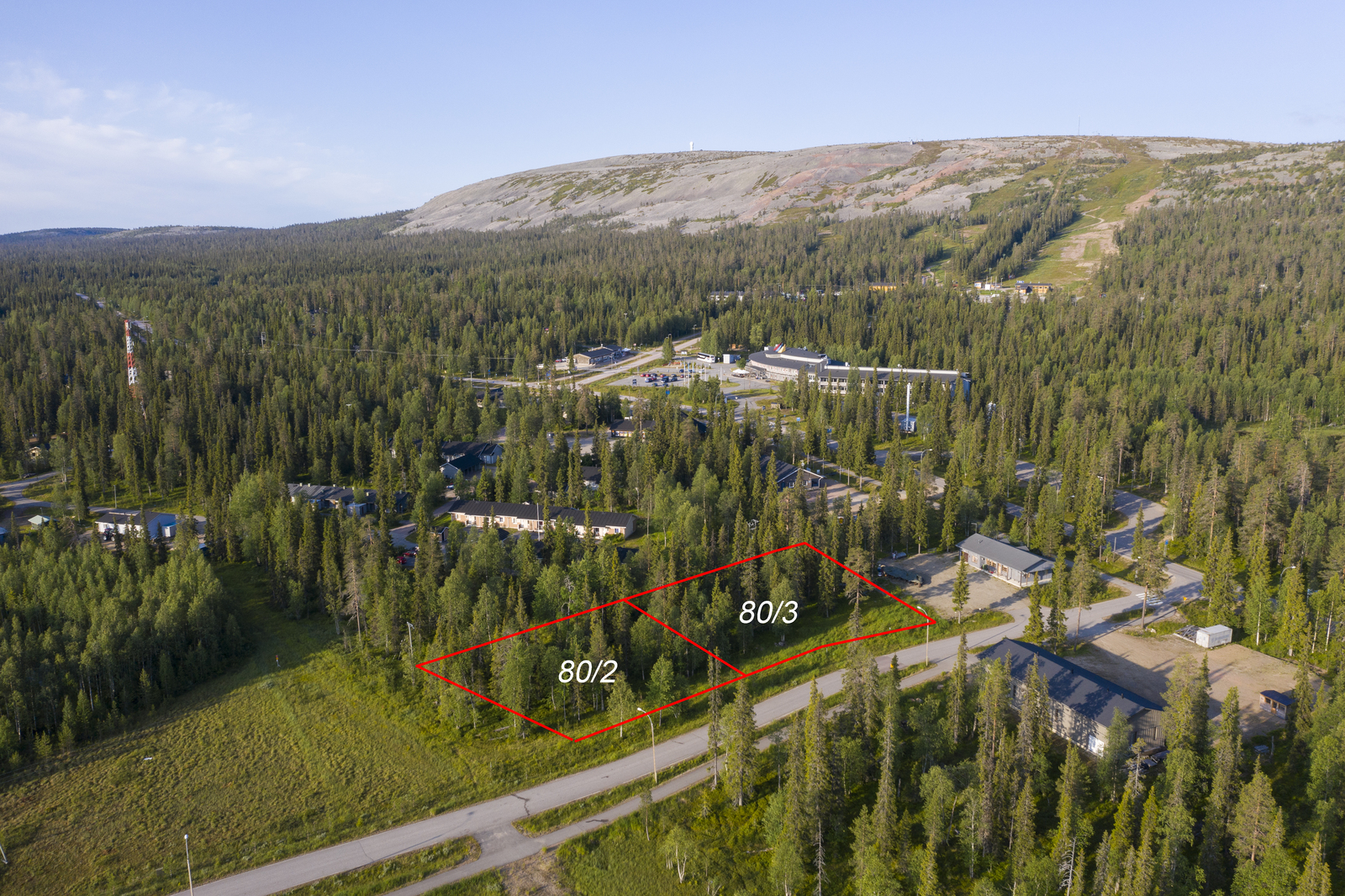 Kahden tontin kaavat piirrettynä metsään matkailukeskusalueelle. Taustalla kohoaa tunturi. Ilmakuva.