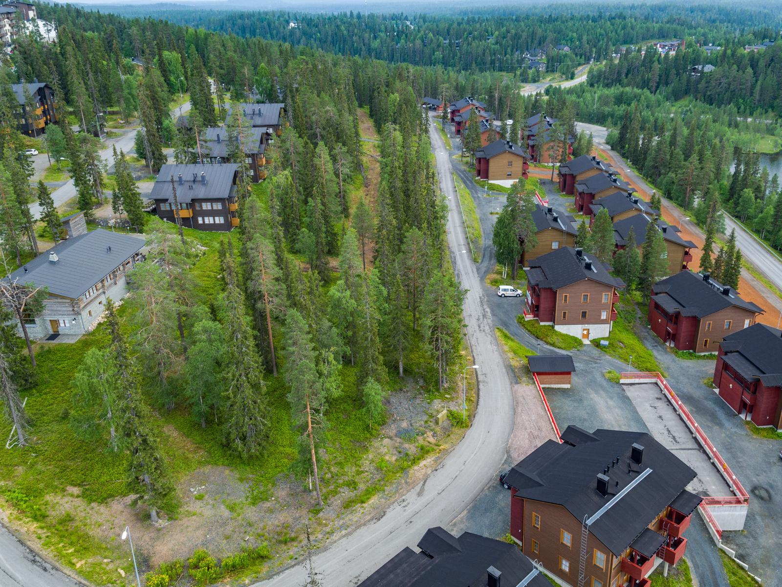 Lomahuoneistoalueella on metsäinen kaistale, jonka ohi kulkee tie. Ilmakuva.