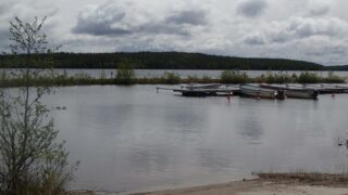 Kesäisessä järvimaisemassa etualalla on veneenlaskupaikka ja taustalla aallonmurtaja.
