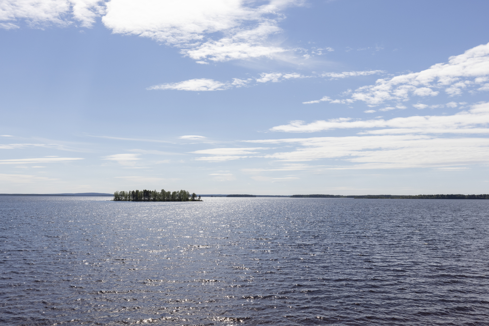 Kesäisessä järvimaisemassa vesi kimmeltää auringonvalossa. Järvenselällä on saari.