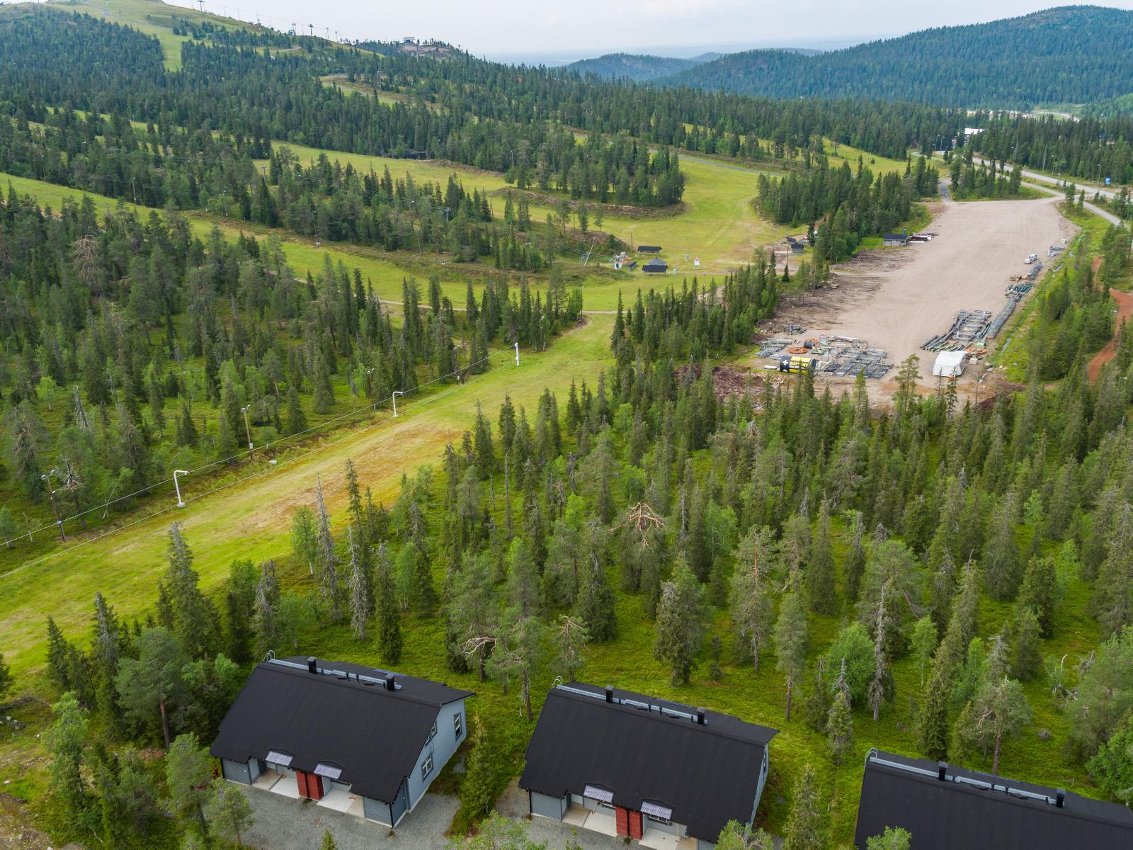 Matkailukeskuksen loma-asuntojen takana kohoaa kesäinen tunturi laskettelurinteineen. Ilmakuva.