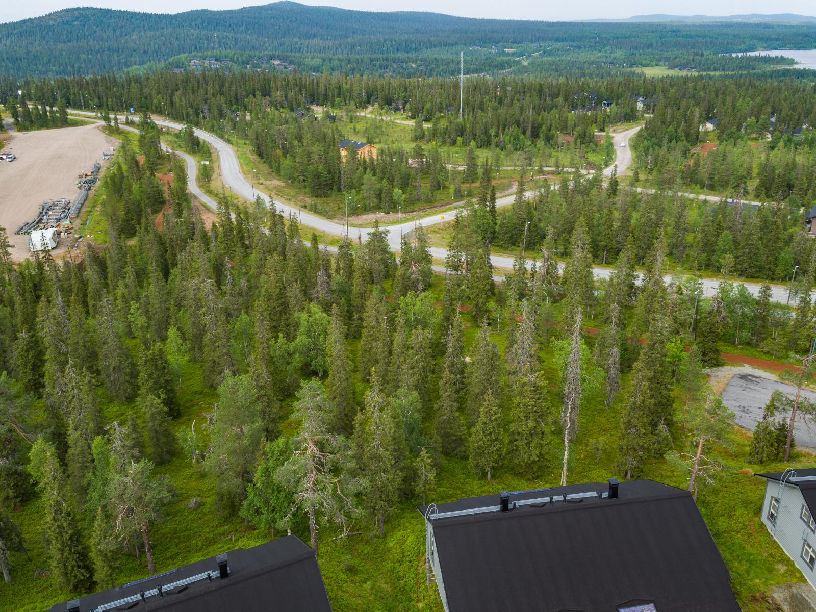 Matkailukeskuksen mökkialueella risteilee teitä. Horisontissa kohoaa tunturimaisema. Ilmakuva.