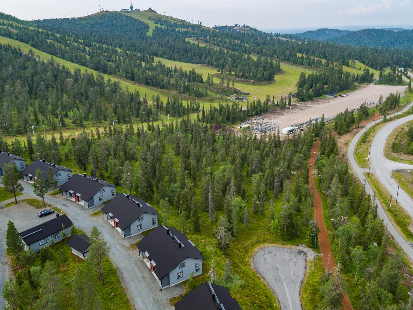 Matkailukeskuksen loma-asuntojen takana kohoaa kesäinen tunturi laskettelurinteineen. Ilmakuva.