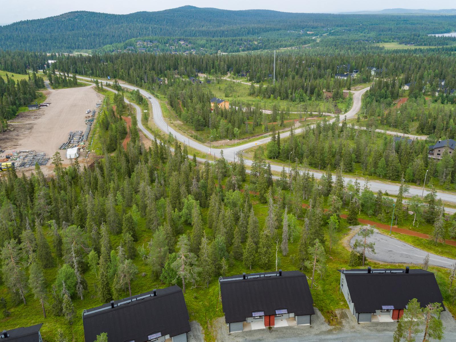 Matkailukeskuksen mökkialueella risteilee teitä. Horisontissa kohoaa tunturimaisema. Ilmakuva.