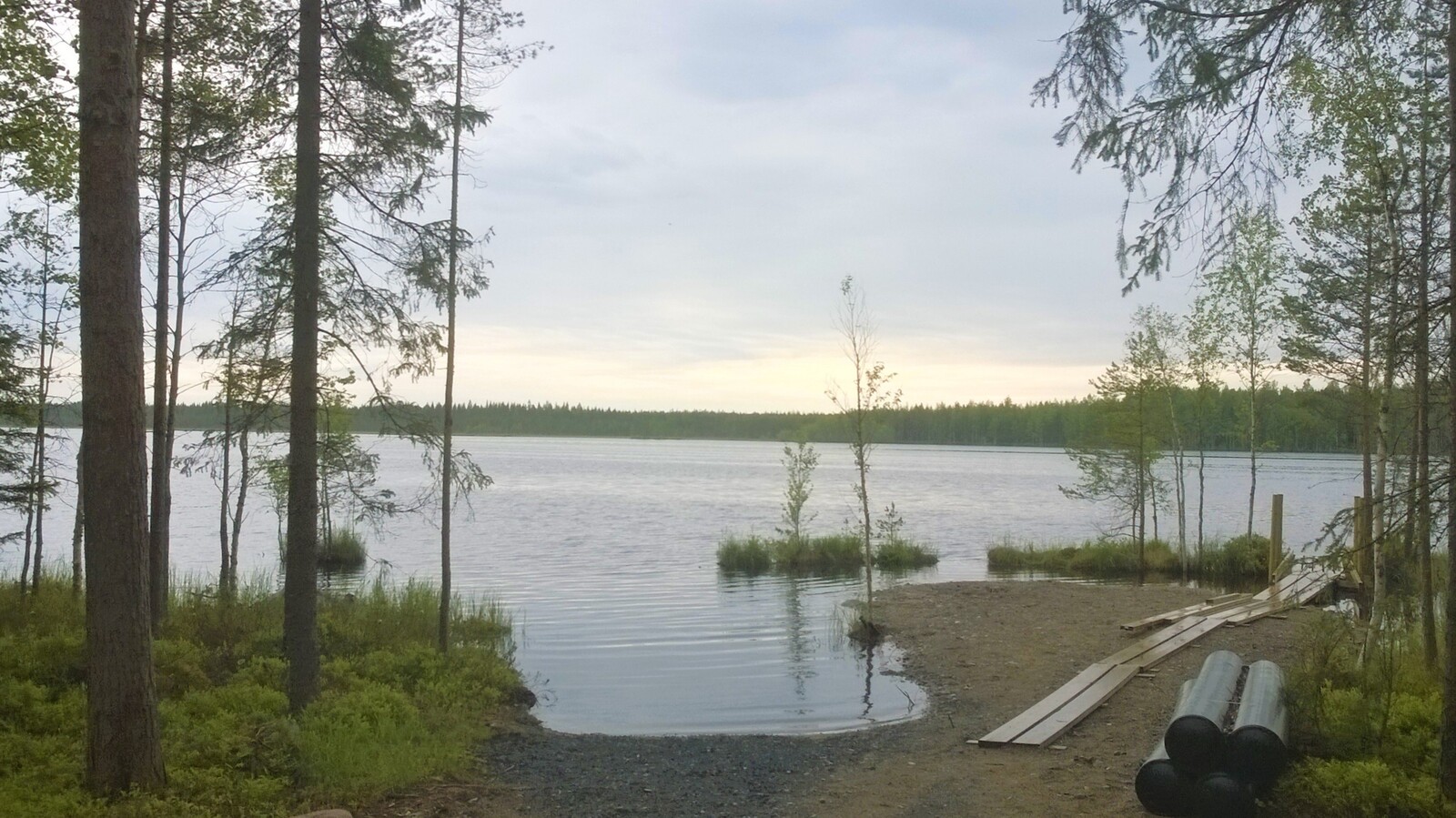 Tontin lähellä sijaitsee ruopattu ranta-alue, jonka vieressä kasvaa kuusia ja koivuja.