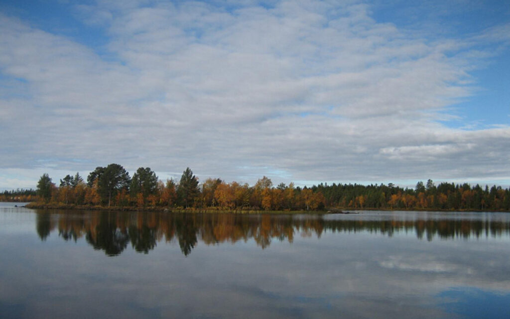 Ruskamaisema rannasta, joka peilautuu järveen.