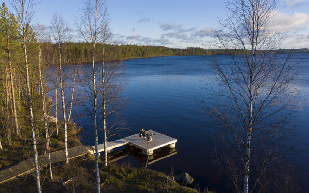 Ilmakuva laiturista, jolla nainen istuu puutarhatuolilla.