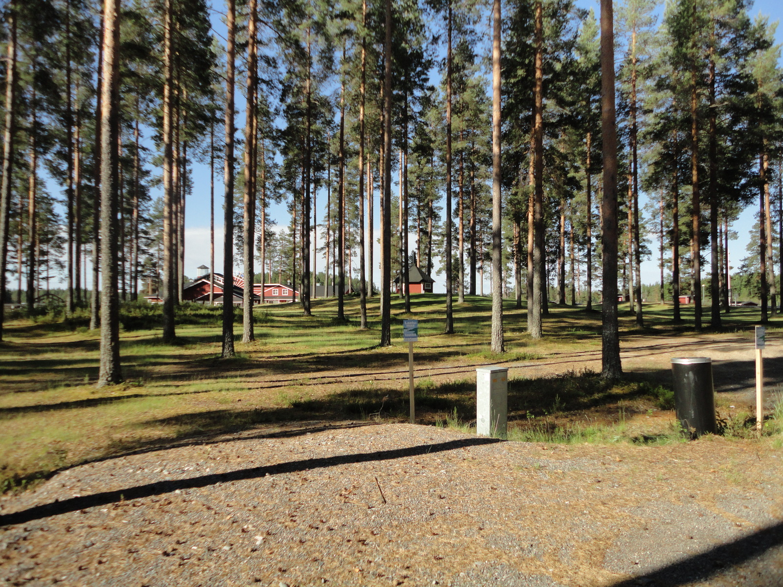 Kortteli 1. Hiekoitetulla alueella Laatumaan kyltti. Puiden takana on Urjanlinnan päärakennus.
