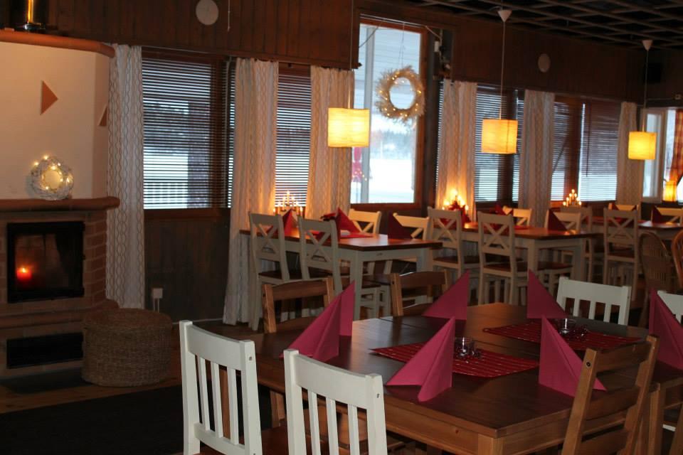 Ravintolan pöydät on katettu ja takassa palaa kynttilä. Ikkunoilla jouluvalot ja kransseja.