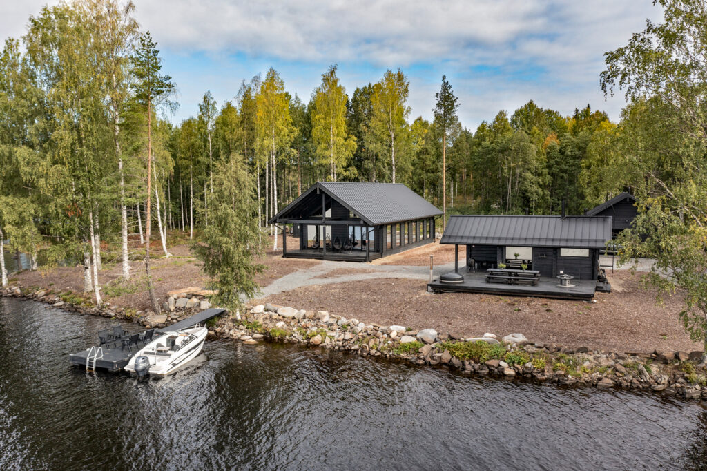 Järveltä otetussa ilmakuvassa näkyy loma-asunto ja piharakennuksia. Järven rannassa on laituri ja laituriin kiinnitetty vene.