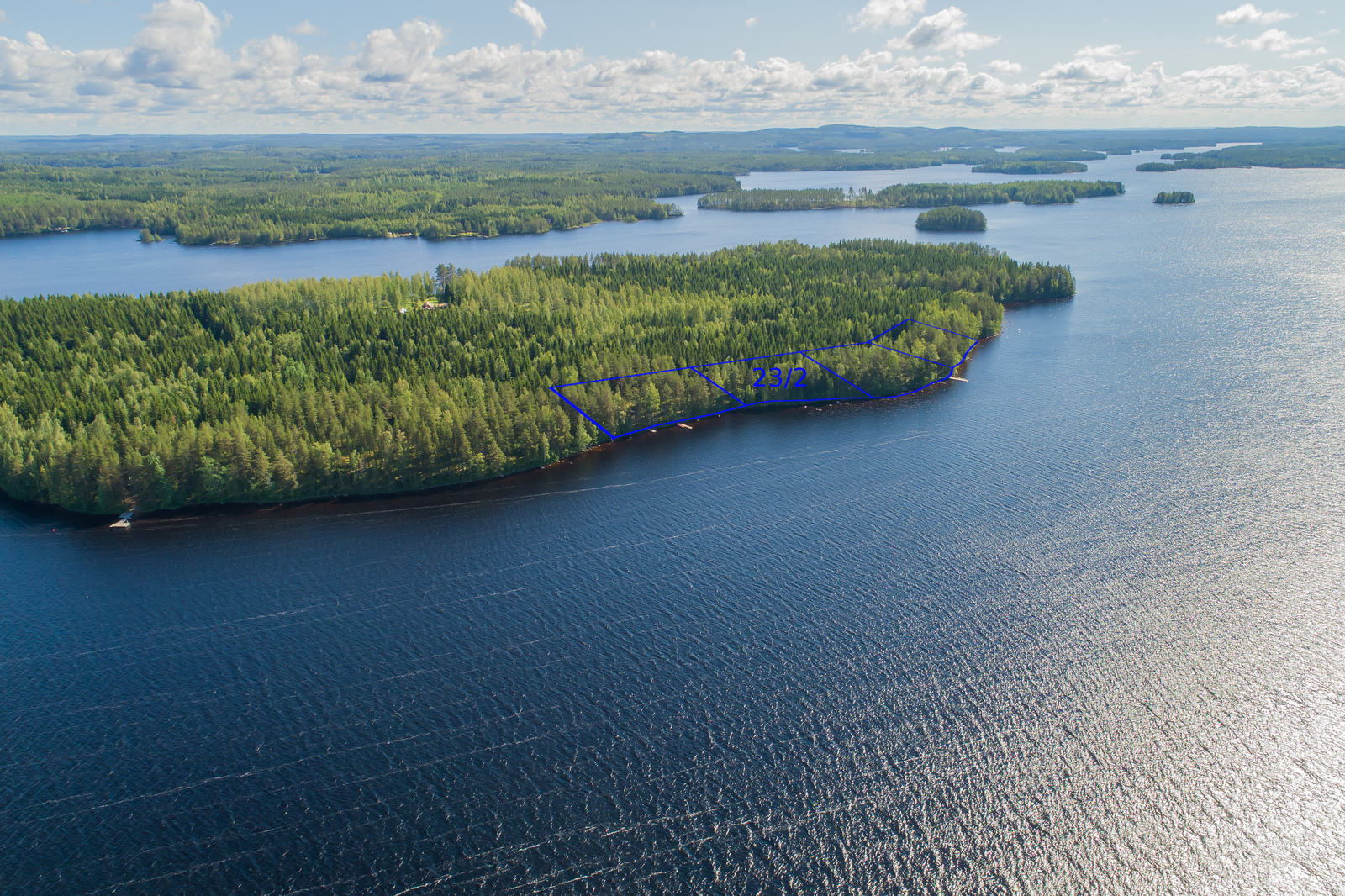 Metsäinen saari järveltä päin katsottuna, tontin rajat piirretty näkyviin.