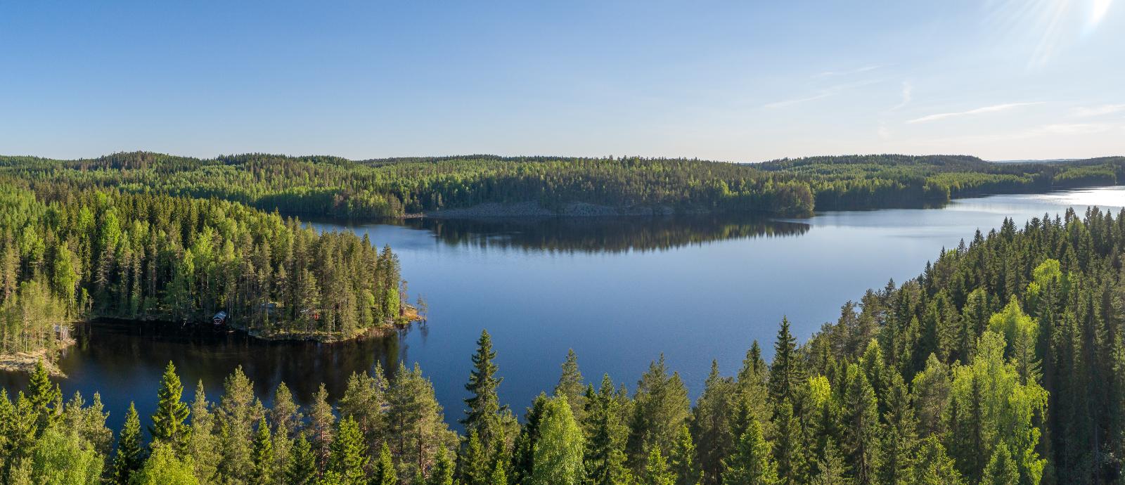 Ilmakuvaa tontin takaa ulapalle. Vastarannan kallio nousee sinisestä järvestä.