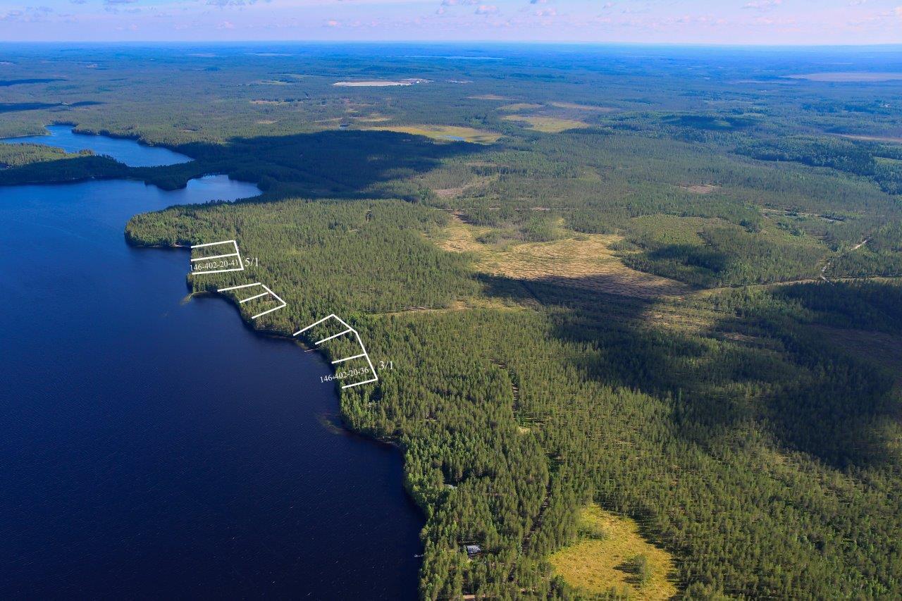 Runsaspuustoista sekametsää aurinkoisen järven rannalla. Näkymä kauas metsien ja soiden keskelle.