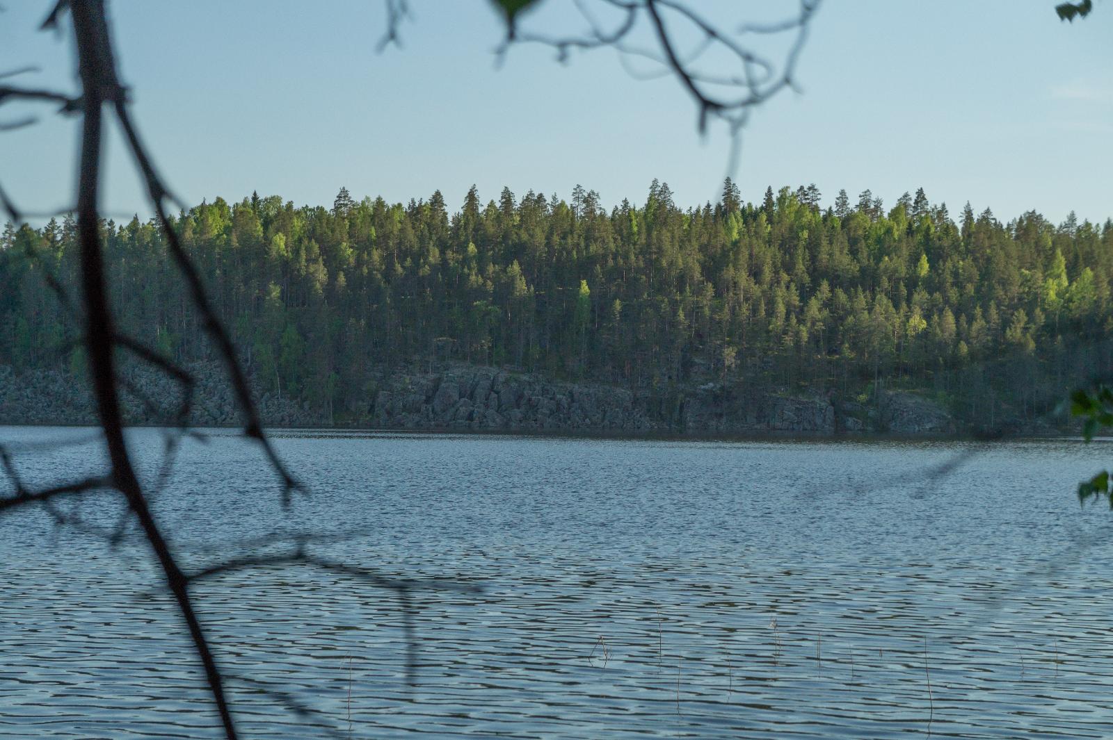 Vastarannalla näkyy kaunis kallio jonka päällä kasvaa puita.