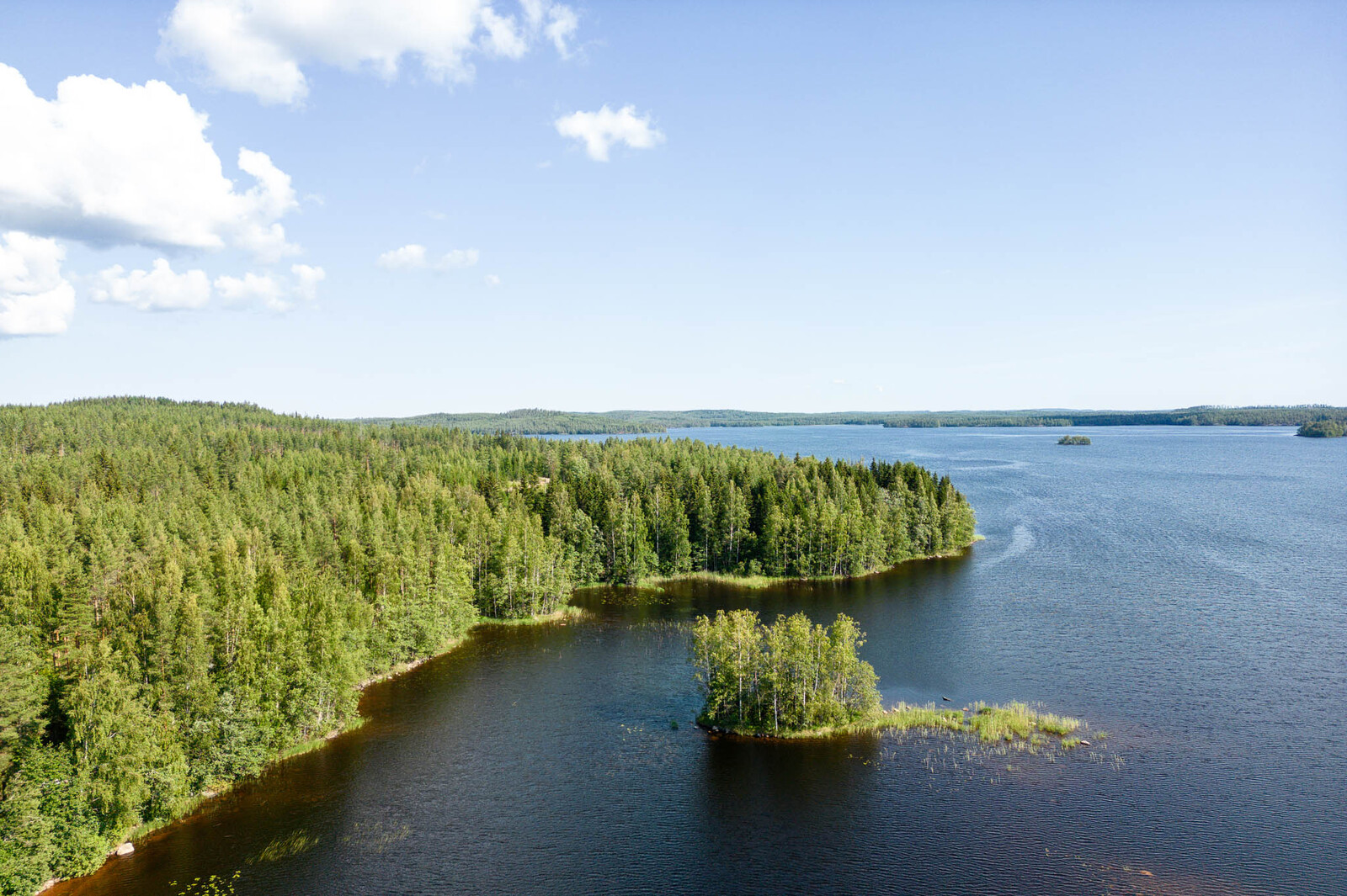 Ilmakuva rannan myötäisesti tonteille ja ulapalle, tonttien edustalla järvessä on saari.