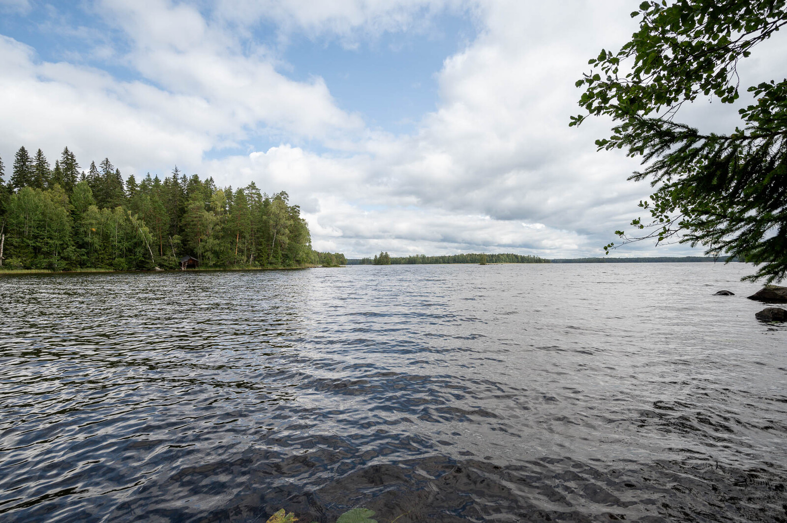 Aaltoileva järvi, taivaalla on valkoharmaita pilviä.