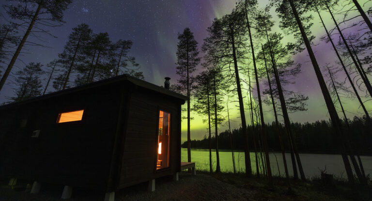 Järven yllä leimuavat pimeässä illassa värikkäät revontulet.