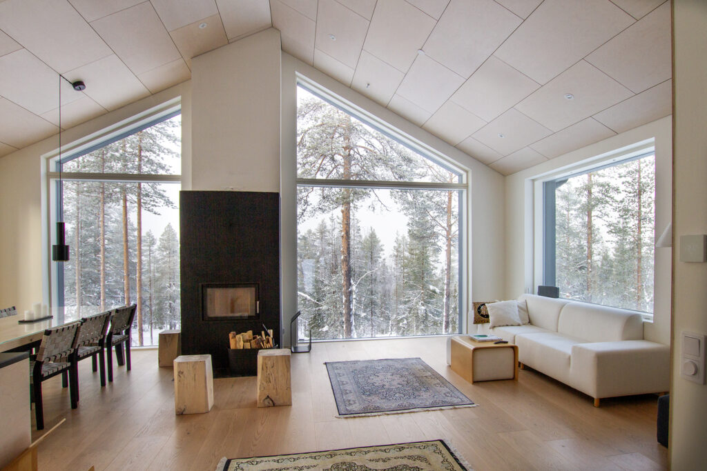 Asunnon suuret ikkunat antavat valoa ja ikkunoista näkyy ympäröivä talvinen metsä.